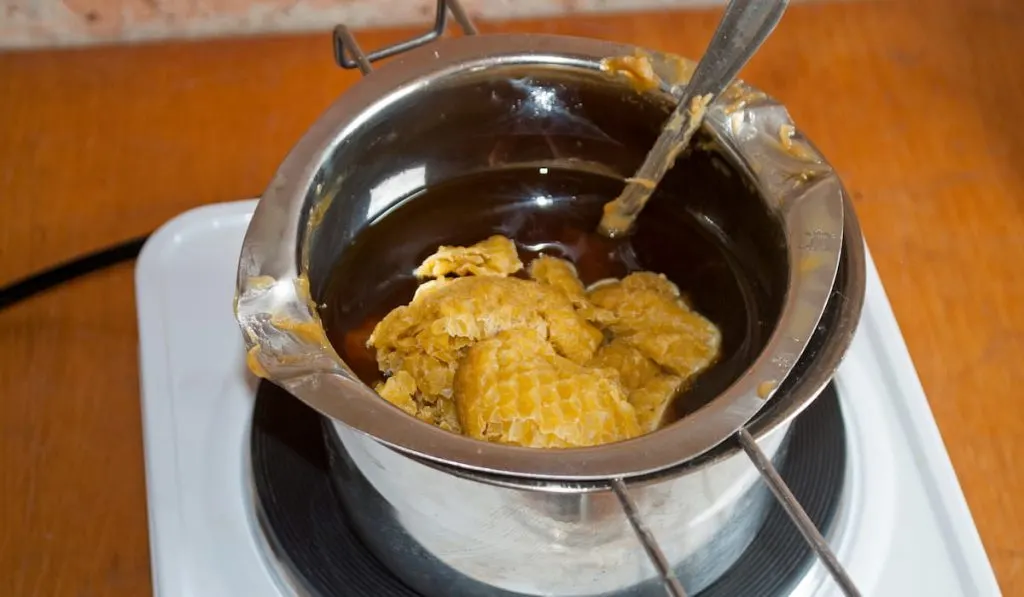 Wax in the process of melting in a metal dish on an electric stove