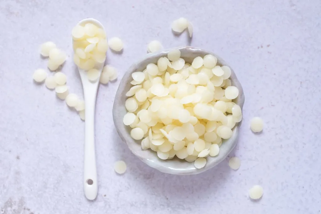 white natural beeswax pellets in white ceranic bowl